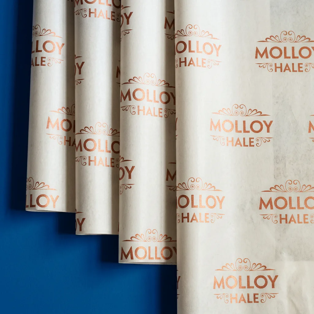 Branded tissue paper with gold logos and ornate all-over print design