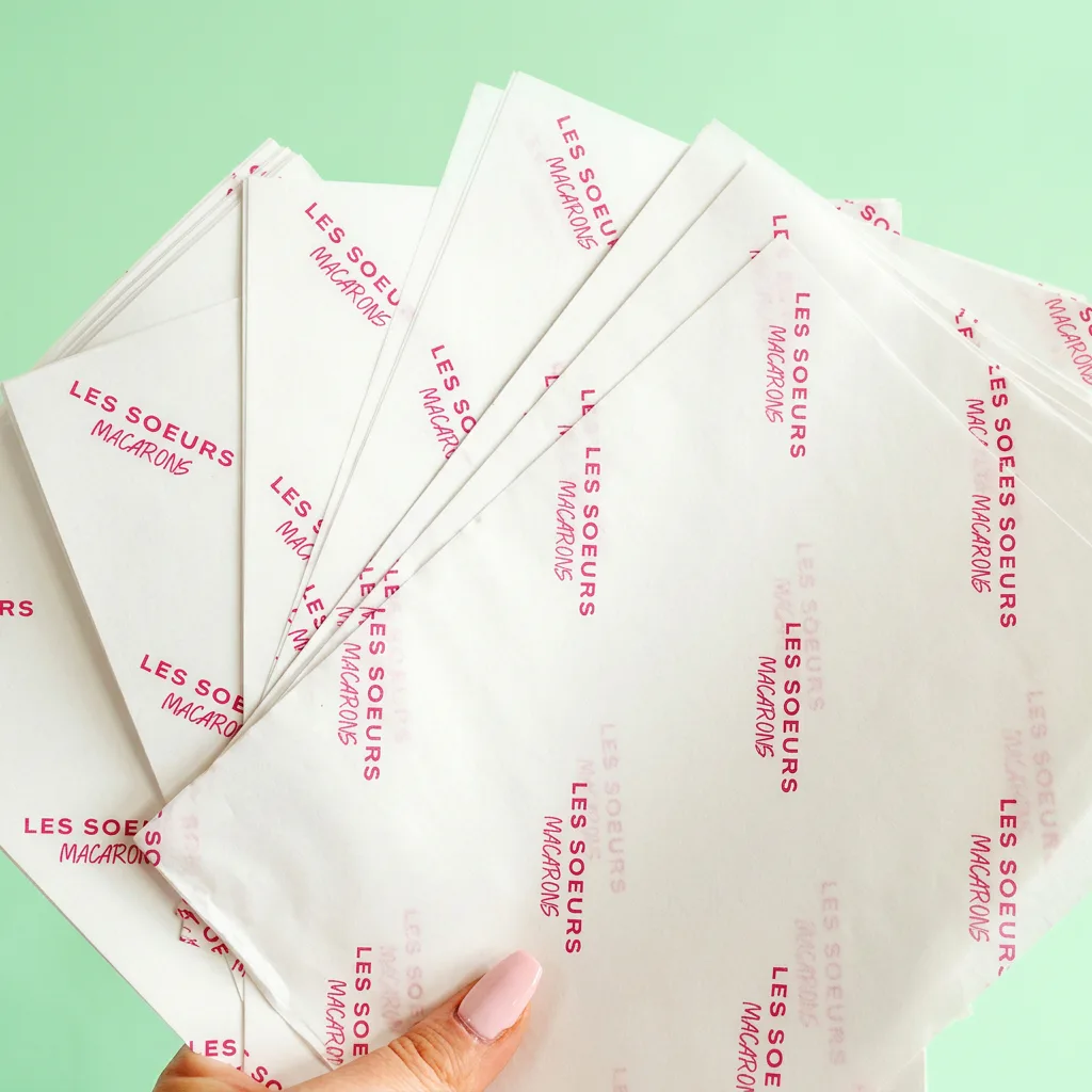 White tissue paper printed with repeating pink retail-brand logos